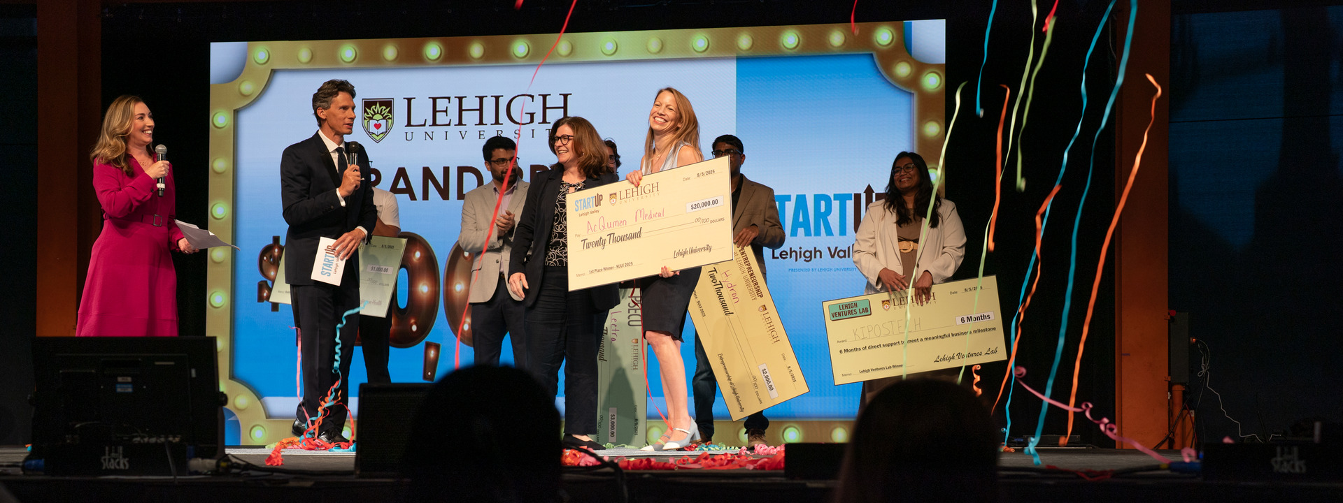 The 2025 SULV winner holds a giant check surrounded by balloons.
